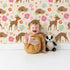 Lovely child standing in front of Whimsy Tots Blossom Meadow Deer Wallpaper in Cream with deer, flower, butterfly, heart in design.