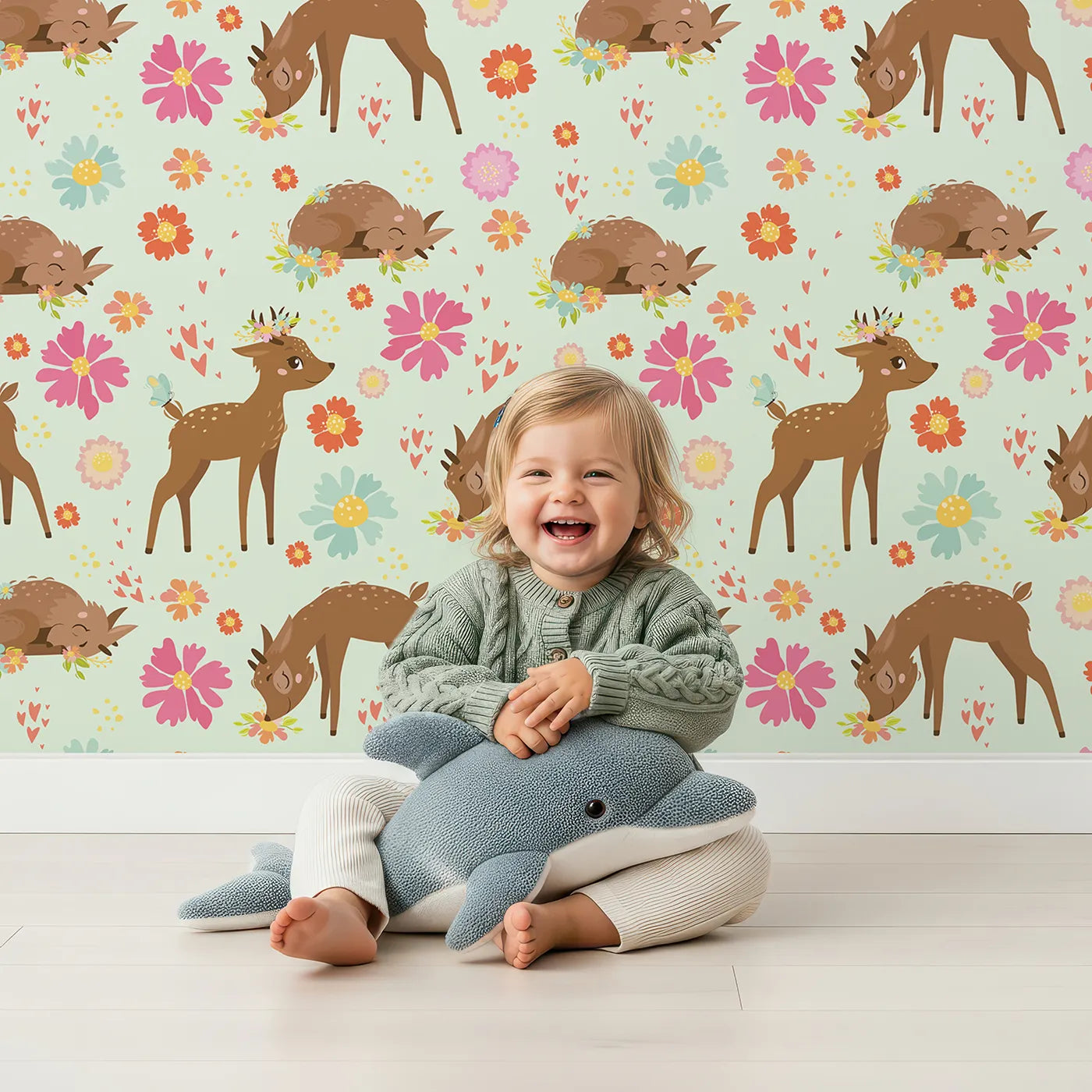 Lovely child standing in front of Whimsy Tots Blossom Meadow Deer Wallpaper in Mint Green with deer, flower, butterfly, heart in design.
