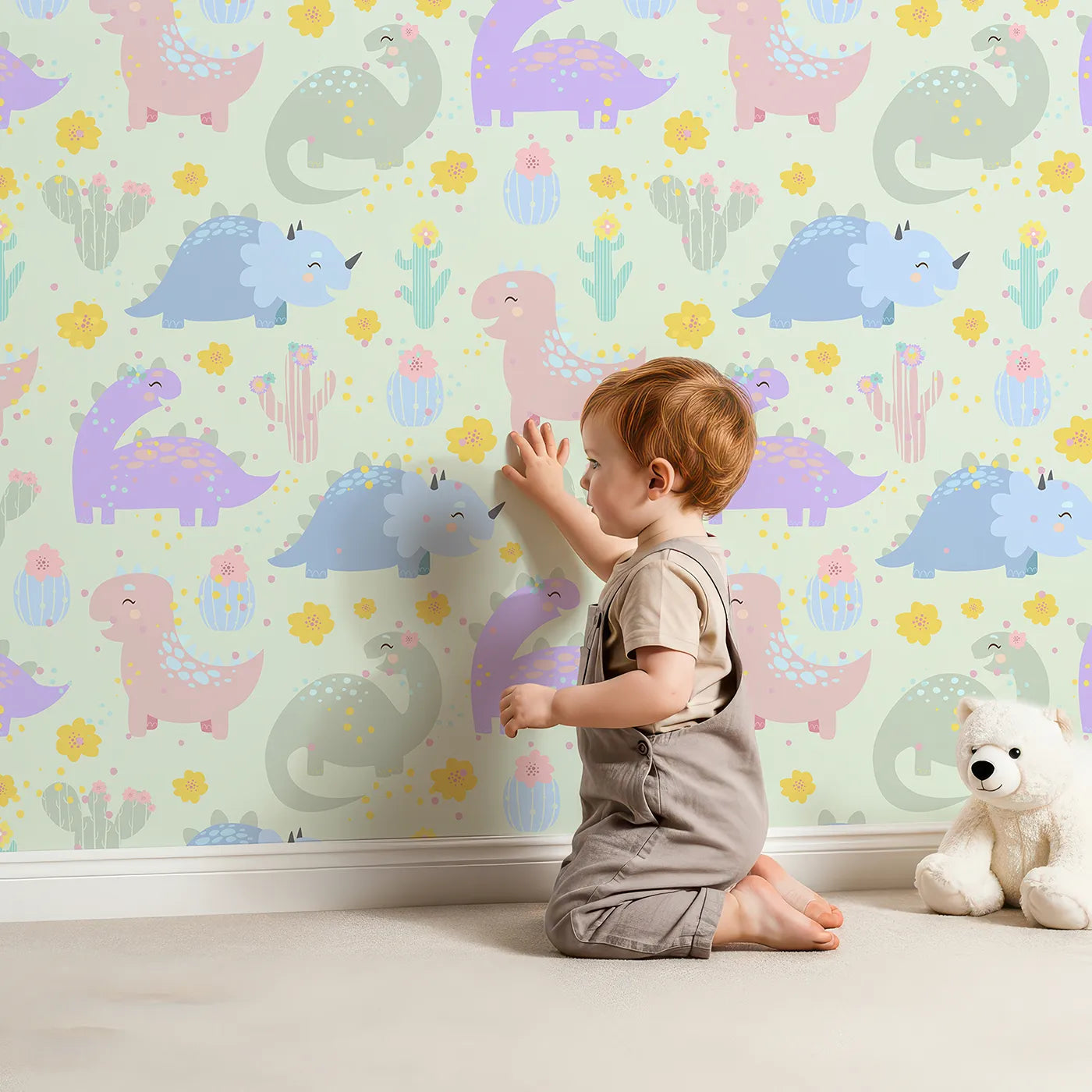 Lovely child standing in front of Whimsy Tots Cactus Dino Parade Wallpaper in Mint Green with dinosaur, cactus, flower in design.
