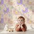 Lovely child standing in front of Whimsy Tots Bouncing Llama Fiesta Wallpaper in Cream with llama, cactus, flower, confetti in design.