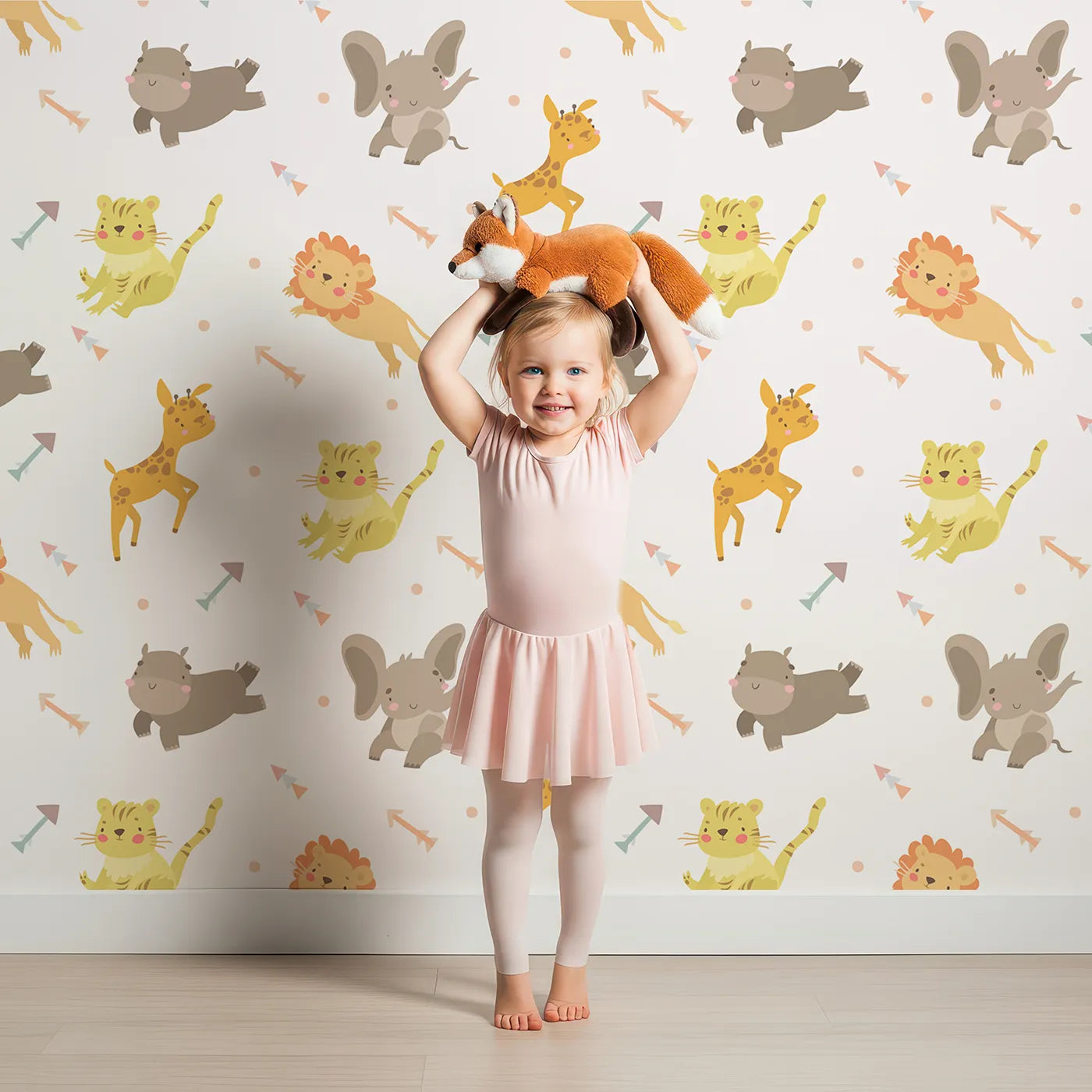 Lovely child standing in front of Whimsy Tots Safari Buddies Parade Wallpaper in Cream with lion, giraffe, elephant, hippo, tiger, arrow in design.