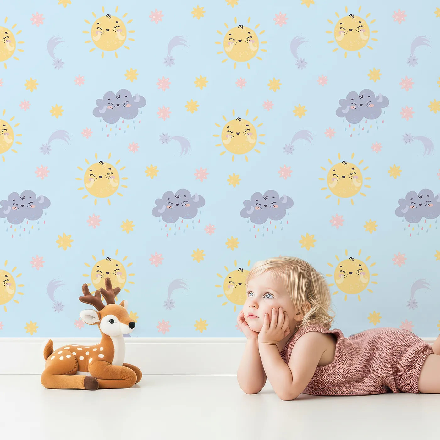 Lovely child standing in front of Whimsy Tots Sun and Cloud Kiss Wallpaper in Sky Blue with sun, cloud, raindrop, flower, star in design.