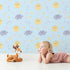 Lovely child standing in front of Whimsy Tots Sun and Cloud Kiss Wallpaper in Sky Blue with sun, cloud, raindrop, flower, star in design.