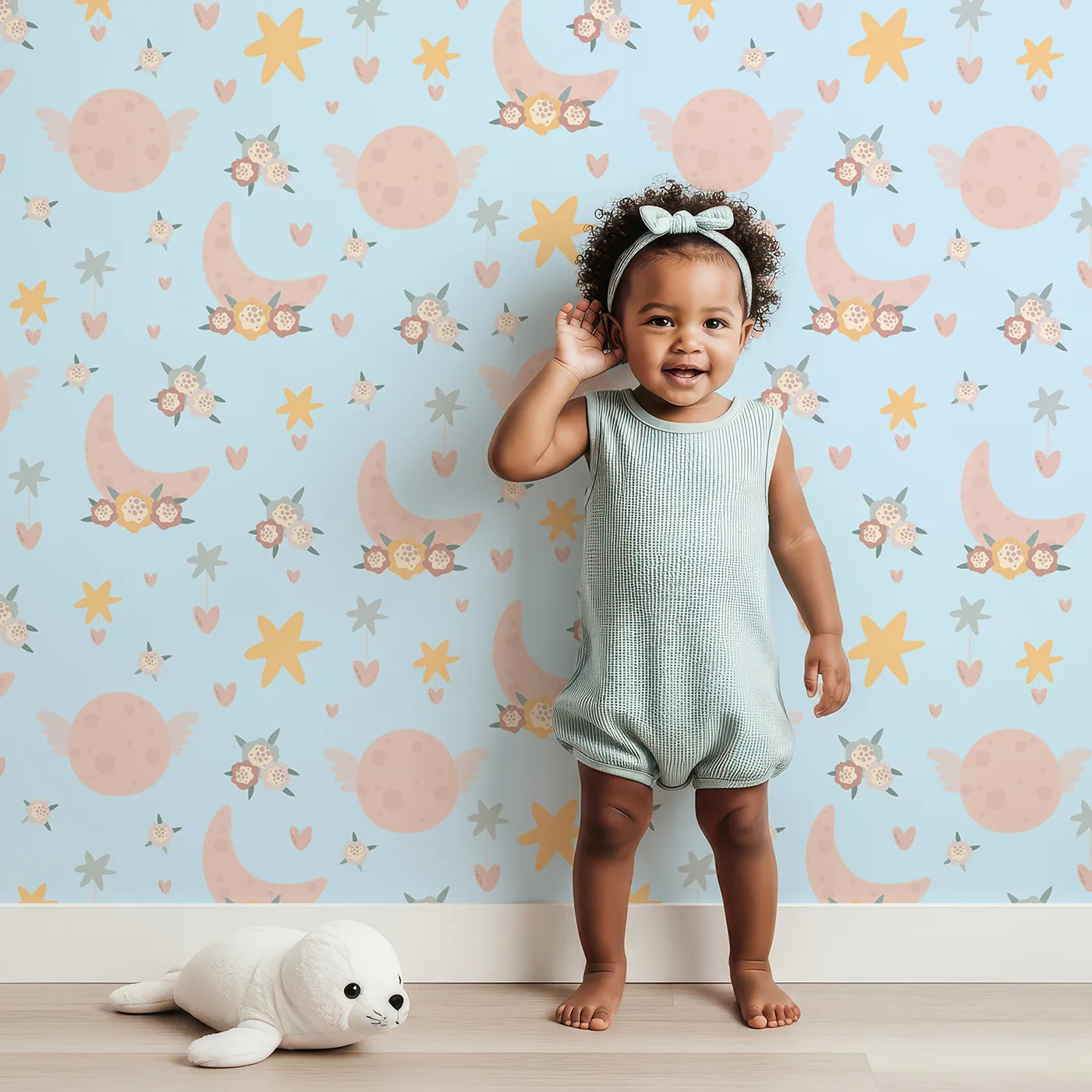 Lovely child standing in front of Whimsy Tots Celestial Petal Dreams Wallpaper in Morning Sky with moon, flower, heart, star, wing in design.