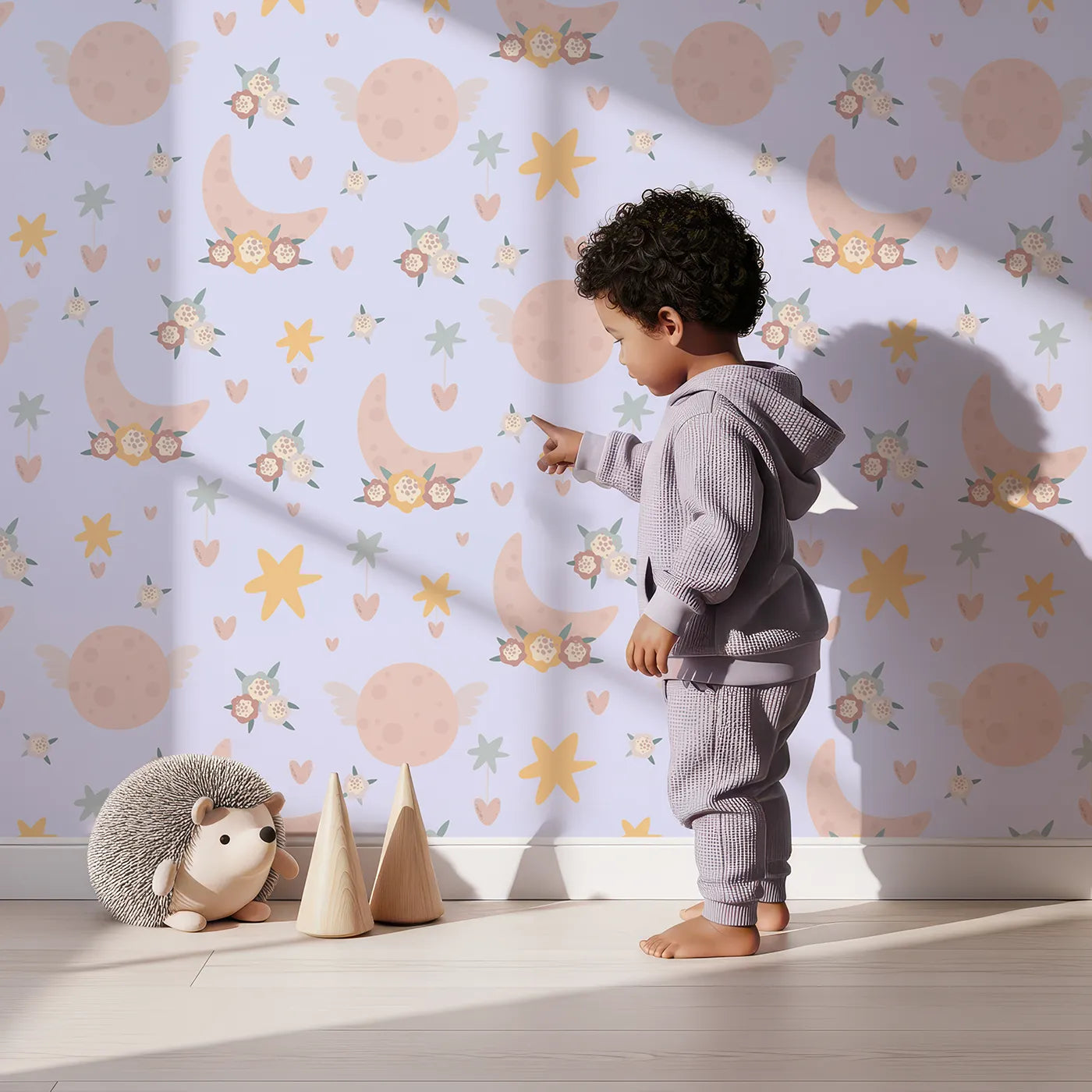 Lovely child standing in front of Whimsy Tots Celestial Petal Dreams Wallpaper in Lavender Mist with moon, flower, heart, star, wing in design.