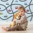 Lovely child standing in front of Whimsy Tots Bumper Buddies Road Maze Wallpaper in Sky Blue with car, road, truck, taxi in design.