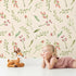 Lovely child standing in front of Whimsy Tots Blossom Meadow Breeze Wallpaper in Cream with flower, leaf, vine, berry in design.