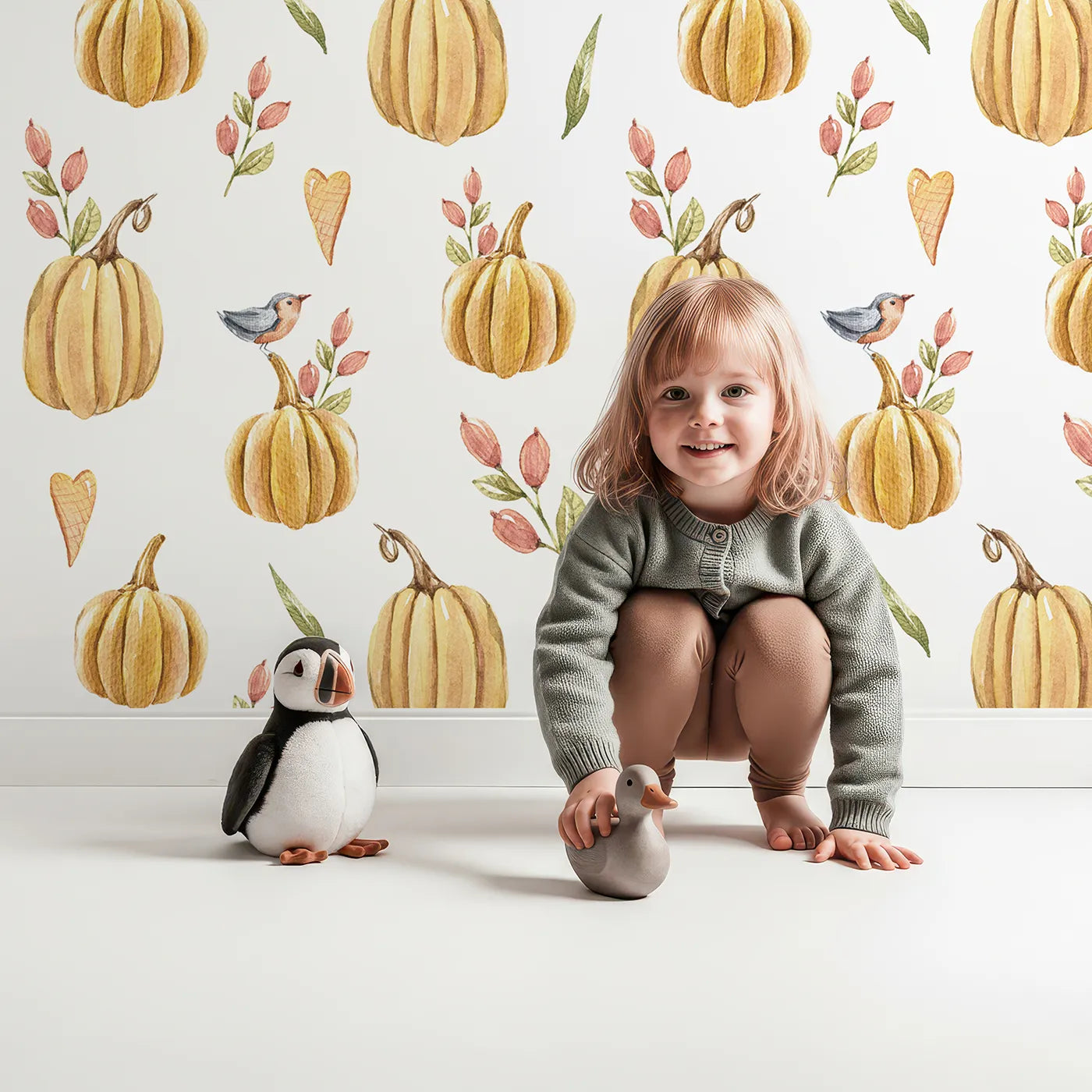 Lovely child standing in front of Whimsy Tots Pumpkin Patch Whimsy Wallpaper in White with pumpkin, bird, heart, leaf in design.