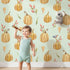 Lovely child standing in front of Whimsy Tots Pumpkin Patch Whimsy Wallpaper in Mint Green with pumpkin, bird, heart, leaf in design.