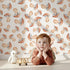 Lovely child standing in front of Whimsy Tots Mushroom Meadow Whispers Wallpaper in White with mushroom in design.