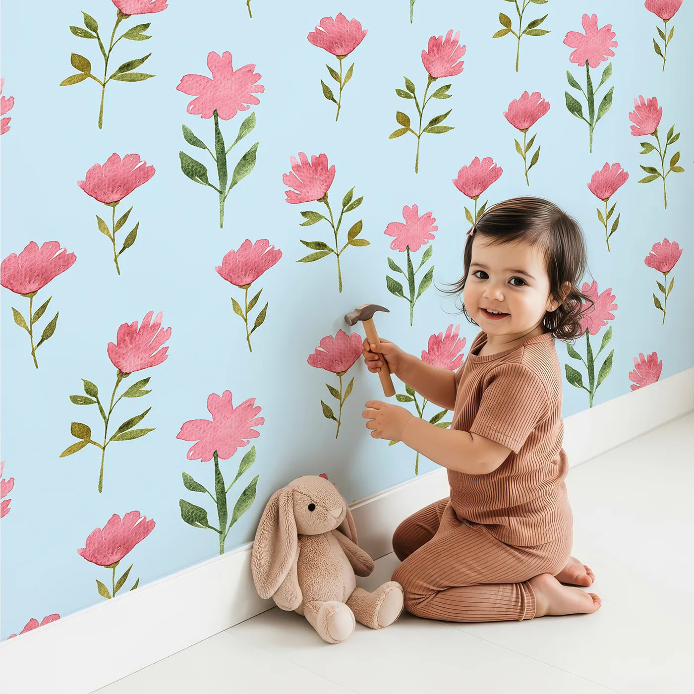 Lovely child standing in front of Whimsy Tots Pink Meadow Blossoms Wallpaper in Sky Blue with flower, leaf in design.