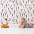 Lovely child standing in front of Whimsy Tots Tulip Meadow Dots Wallpaper in Blush Pink with flower, leaf, tulip in design.