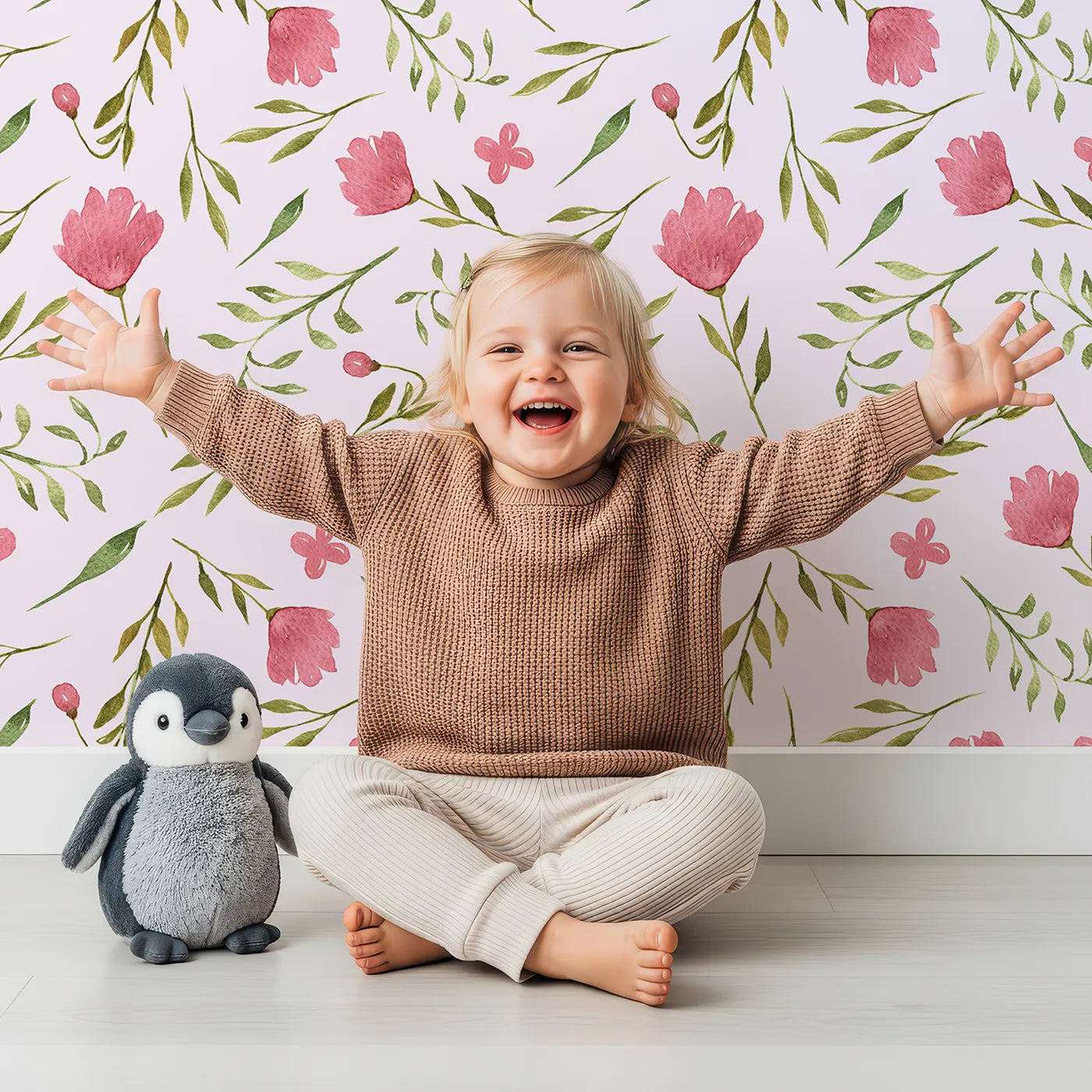 Lovely child standing in front of Whimsy Tots Blushing Petal Tangle Wallpaper in Blush Pink with flower, leaf, petal, vine in design.