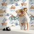 Lovely child standing in front of Whimsy Tots Sky Explorers Wallpaper in White with fish, submarine, balloon, ship, sky, cloud in design.