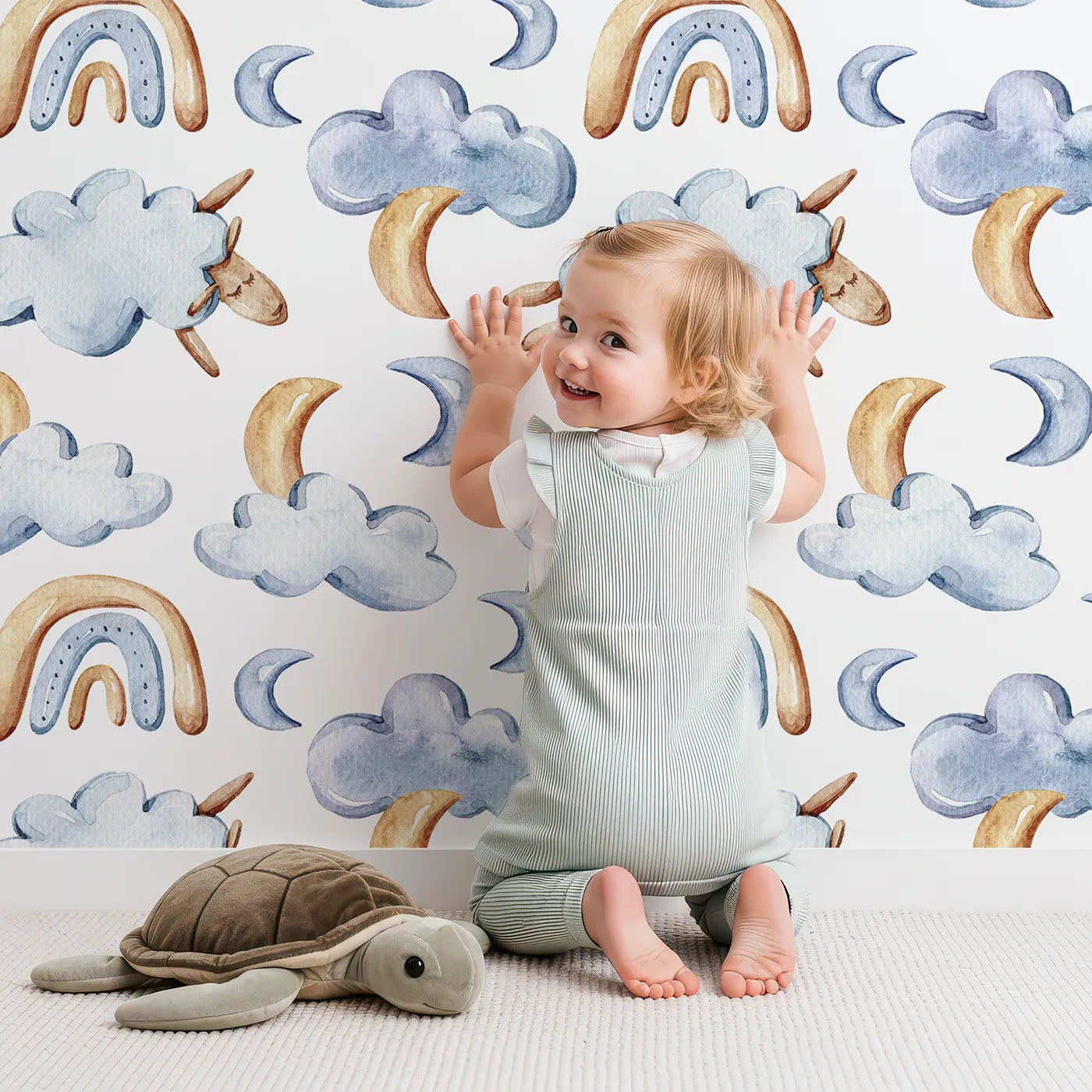 Lovely child standing in front of Whimsy Tots Sleepy Skies Wallpaper in White with cloud, moon, rainbow, sheep in design.