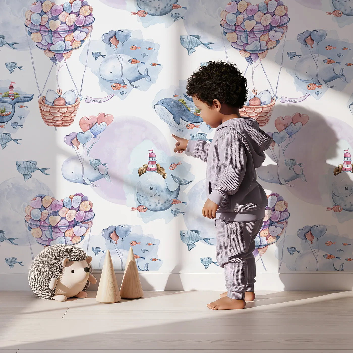Lovely child standing in front of Whimsy Tots Whales of Love Wallpaper in White with whale, balloon, heart, lighthouse, fish in design.