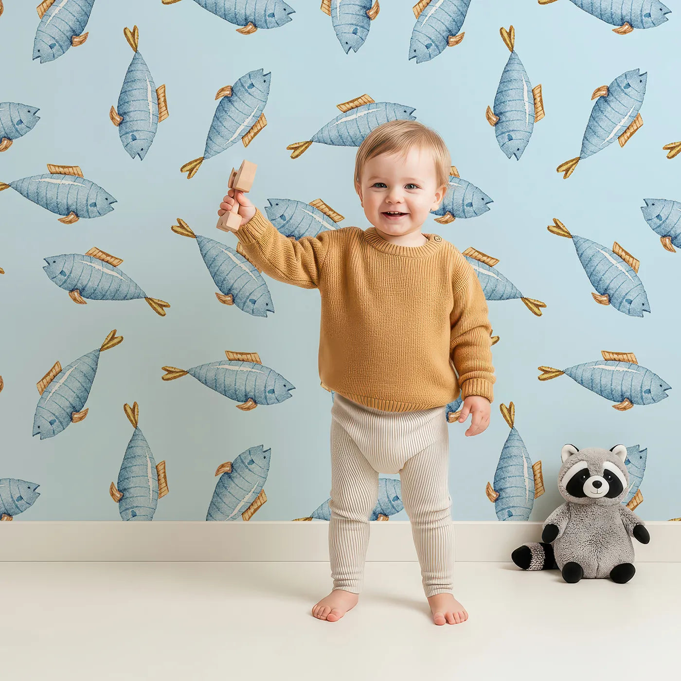 Lovely child standing in front of Whimsy Tots Little Swimmer Fish Wallpaper in Blue with fish in design.
