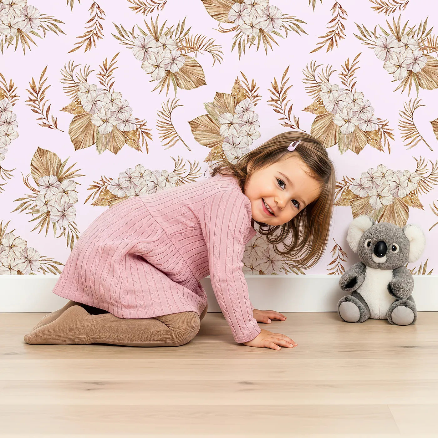 Lovely child standing in front of Whimsy Tots Dried Bloom Cascade Wallpaper in Pink with flower, palm, leaf in design.