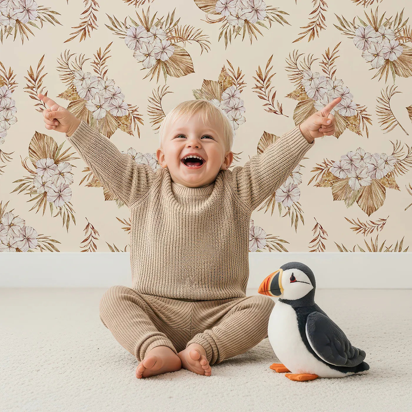 Lovely child standing in front of Whimsy Tots Dried Bloom Cascade Wallpaper in Cream with flower, palm, leaf in design.