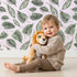 Lovely child standing in front of Whimsy Tots Monsoon Leaf Drift Wallpaper in Pink with leaf in design.