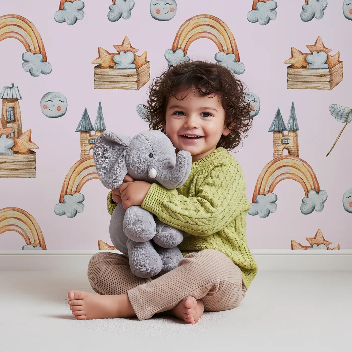 Lovely child standing in front of Whimsy Tots Rainbow Castle Dreams Wallpaper in Pink with castle, rainbow, moon, cloud, star, net in design.