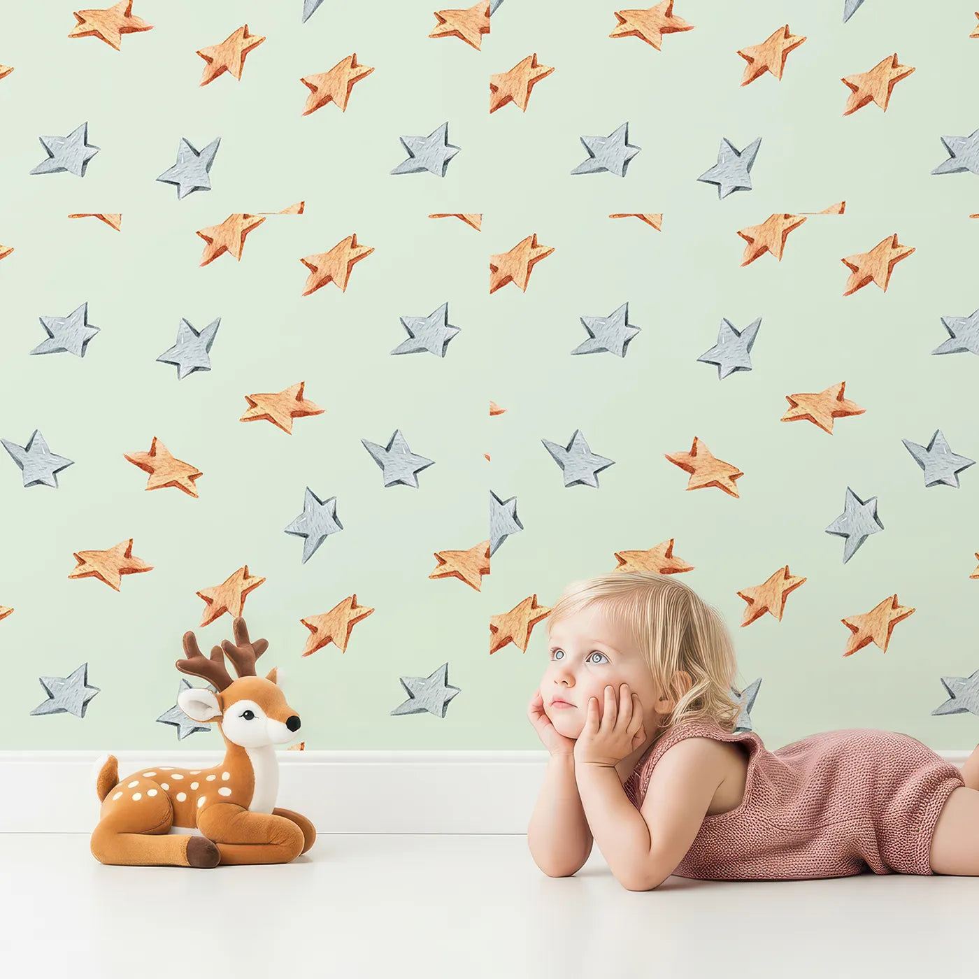 Lovely child standing in front of Whimsy Tots Wooden Star Sprinkle Wallpaper in Mint Green with wooden, star, sprinkle, wallpaper in design.