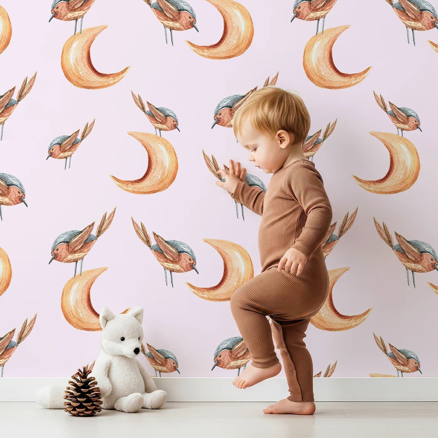 Lovely child standing in front of Whimsy Tots Moon Perch Birds Wallpaper in Pink with bird, moon in design.
