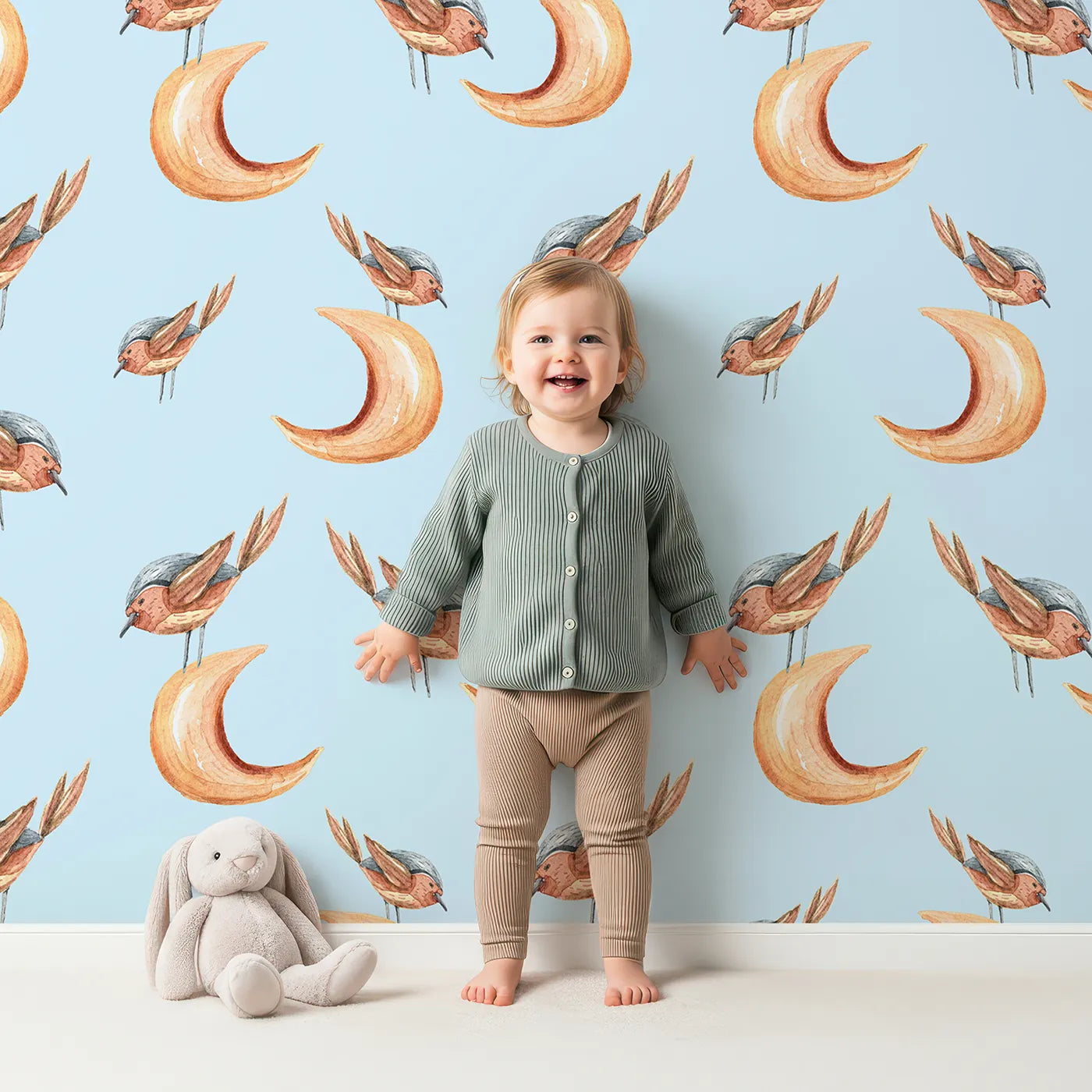 Lovely child standing in front of Whimsy Tots Moon Perch Birds Wallpaper in Blue with bird, moon in design.