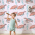 Lovely child standing in front of Whimsy Tots Gentle Ocean Turtles Wallpaper in Pink with turtle, bubble in design.