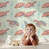 Lovely child standing in front of Whimsy Tots Gentle Ocean Turtles Wallpaper in Green with turtle, bubble in design.