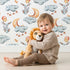 Lovely child standing in front of Whimsy Tots Starry Bunny Balloons Wallpaper in White with bunny, balloon, star, cloud, moon in design.