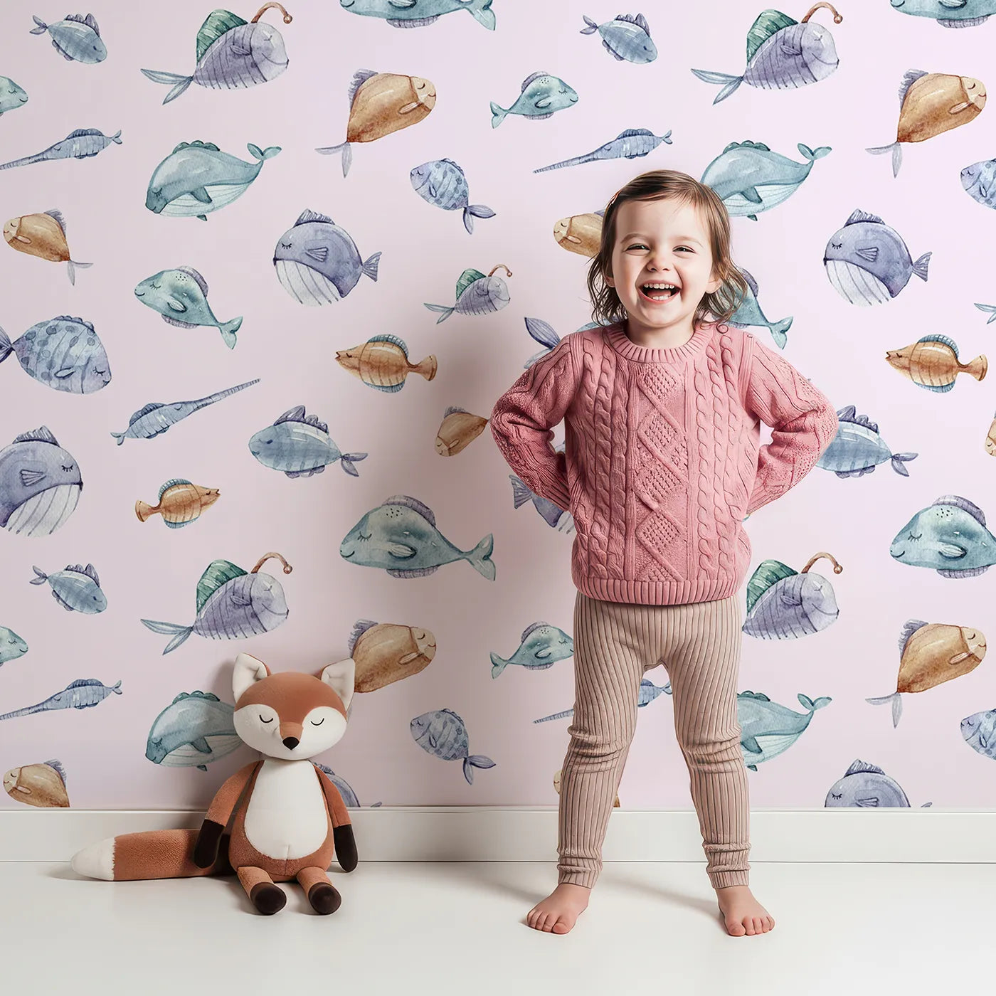 Lovely child standing in front of Whimsy Tots Dreamy Fish Parade Wallpaper in Pink with fish, fin, puffer, anglerfish, goby in design.