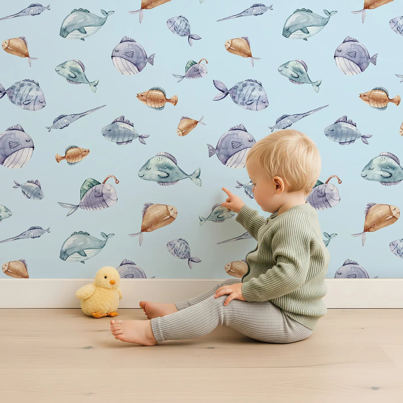 Lovely child standing in front of Whimsy Tots Dreamy Fish Parade Wallpaper in Sky Blue with fish, fin, puffer, anglerfish, goby in design.