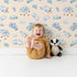 Lovely child standing in front of Whimsy Tots Counting Cloud Sheep Wallpaper in Cream with cloud, sheep, star, mobile in design.