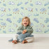 Lovely child standing in front of Whimsy Tots Counting Cloud Sheep Wallpaper in Mint Green with cloud, sheep, star, mobile in design.