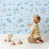 Lovely child standing in front of Whimsy Tots Counting Cloud Sheep Wallpaper in Sky with cloud, sheep, star, mobile in design.