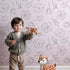 Lovely child standing in front of Whimsy Tots Line Art Bloom Wallpaper in Blush Pink with flower, blossom, lineart, leaf in design.