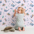 Lovely child standing in front of Whimsy Tots Ocean Galaxy Friends in Blush Pink with whale, turtle, ufo, balloon, moon, fish, splash, star, narwhal in design.