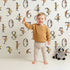 Lovely child standing in front of Whimsy Tots Botanical Numbers Grid in White with number, leaf, branch, stem in design.