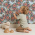 Lovely child standing in front of Whimsy Tots Autumn Bloom Cascade in Blue with flower, petal, leaf, vine in design.