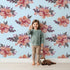 Lovely child standing in front of Whimsy Tots Berry Blush Blooms in Sky with flower, petal, leaf, sprig in design.