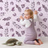 Lovely child standing in front of Whimsy Tots Lavender Leaves Whisper in Blush with leaf, sprig, branch in design.
