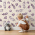 Lovely child standing in front of Whimsy Tots Lavender Leaves Whisper in Sand with leaf, sprig, branch in design.