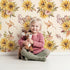 Lovely child standing in front of Whimsy Tots Sun-Kissed Meadow Blooms in Oat with sunflower, flower, leaf, bouquet in design.