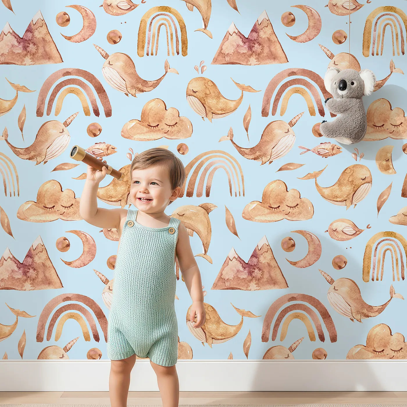Lovely child standing in front of Whimsy Tots Whimsical Earth Friends Wallpaper in Sky Blue with whale, dolphin, narwhal, bird, fish, rainbow, moon, mountain, cloud in design.