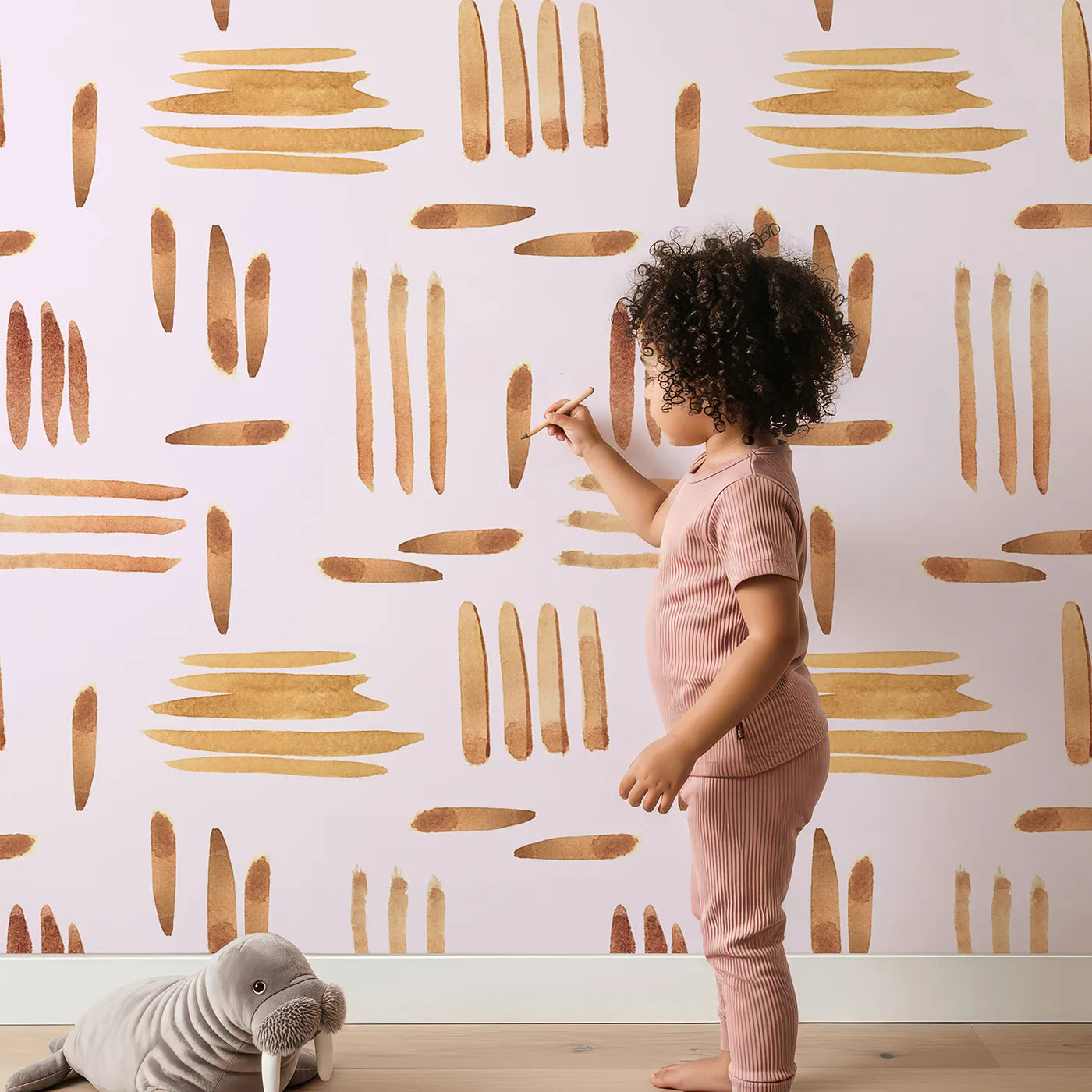 Lovely child standing in front of Whimsy Tots Painted Rhythm Wallpaper in Blush Pink with line, brushstroke in design.
