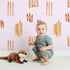 Lovely child standing in front of Whimsy Tots Painted Simplicity Wallpaper in Blush Pink with line, brushstroke in design.