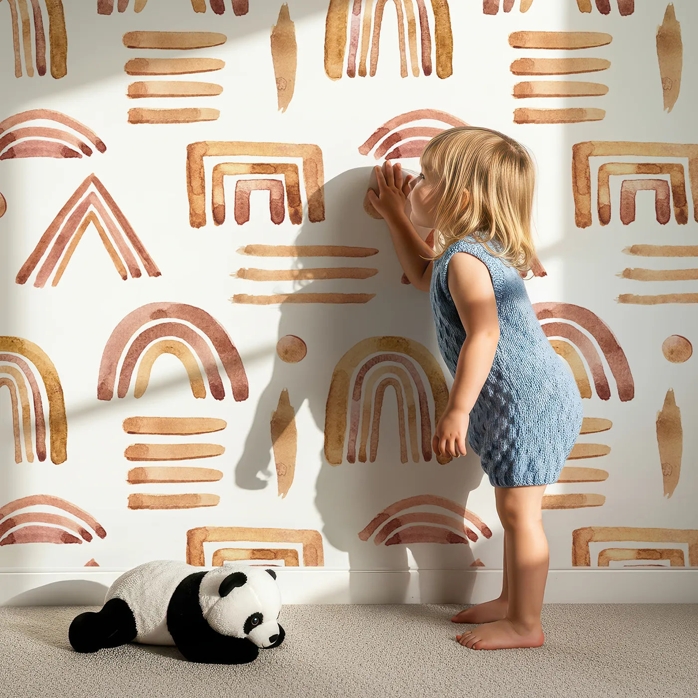 Lovely child standing in front of Whimsy Tots Sun-Drenched Shapes Wallpaper in White with rainbow, shape, brushstroke, line, dot in design.