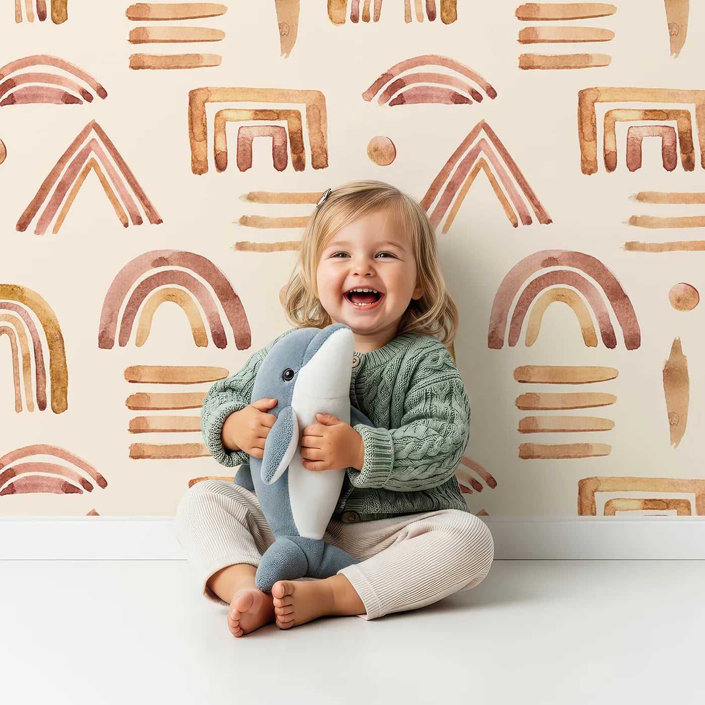 Lovely child standing in front of Whimsy Tots Sun-Drenched Shapes Wallpaper in Blush Pink with rainbow, shape, brushstroke, line, dot in design.