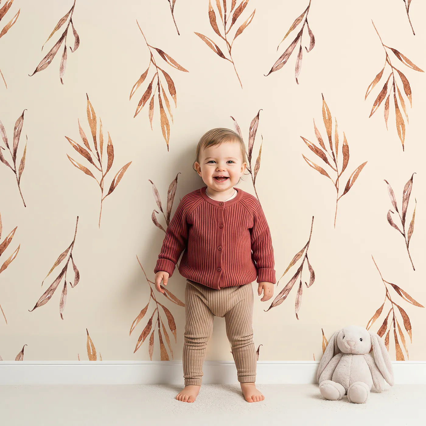 Lovely child standing in front of Whimsy Tots Rustle and Grace Wallpaper in Cream with branch, leaf, stem, botanical in design.
